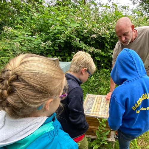 Imker mit Kindern am Bienenstand